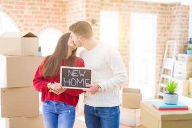 Güzel genç çift aşık ve yeni bir ev için mutlu gülümseyen yeni bir eve hareketli tahta tutarak sarılmak