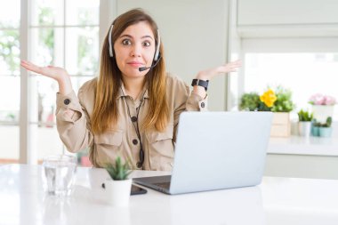Güzel genç operatör kadın dizüstü bilgisayar ile çalışan ve koltuk clueless giyen ve kollarını ve elleri ile karışık ifade kaldırdı. Şüphe kavramı.