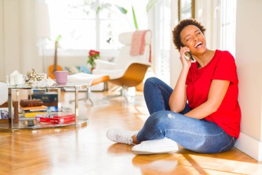 Telefon gülümseyen üzerinde muhabbet katta oturan güzel genç Afro-Amerikan kadın