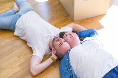 Yeni bir evin katında yatan aşık genç çift, yeni bir daireye taşınmak için çok mutlu gülümseyen, karton kutular civarı