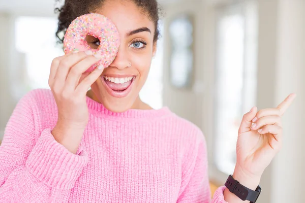 若いですアフリカ系アメリカ人の女の子食べる甘いですピンクドーナツ非常に幸せなポインティングとともに手と指へザ側 — ストック写真