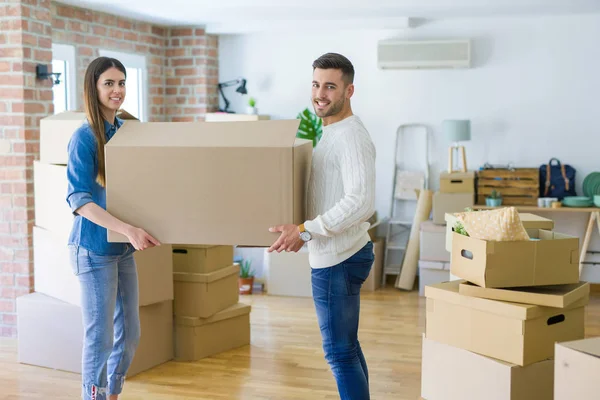 stock image Beautiful young couple moving to a new home, holding big cardboard box