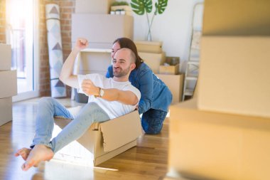 Komik ve çılgın çift bir araba olarak bir cardboad kutusu sürme eğlenceli sahip, mutlu gülümseyen ve yeni evde gülüyorsun