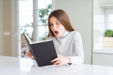 Evde kitap okuyan güzel genç kız sürpriz bir yüzle şokta korkmuş, korku yla korkmuş ve heyecanlı ifade