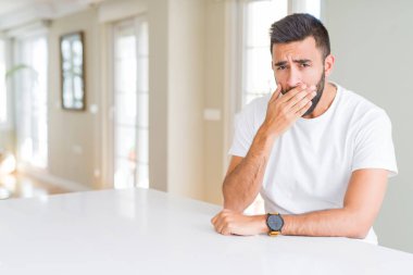 Yakışıklı İspanyol adam evde rahat beyaz t-shirt el ile ağız kapsayan yorgun esneme sıkılmış. Huzursuz ve uykululuk.