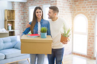 Güzel genç çift yeni bir ev, yeni bir dairede mutlu tutan karton kutular gülümseyen hareket