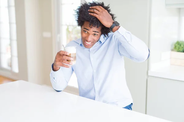 African American man with afro hair drinking a cup of coffee stressed with hand on head, shocked with shame and surprise face, angry and frustrated. Fear and upset for mistake.