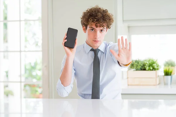 Młody Biznesmen Pokazuje Ekran Smartfona Biurze Otwartą Ręką Robi Znak — Zdjęcie stockowe