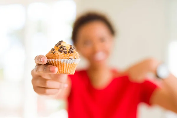 年轻的非洲裔美国妇女吃巧克力片松饼与惊喜的脸指向自己的手指 — 图库照片