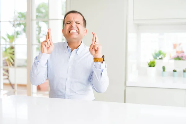 Hombre Mediana Edad Sentado Casa Sonriendo Cruzando Los Dedos Con — Foto de Stock