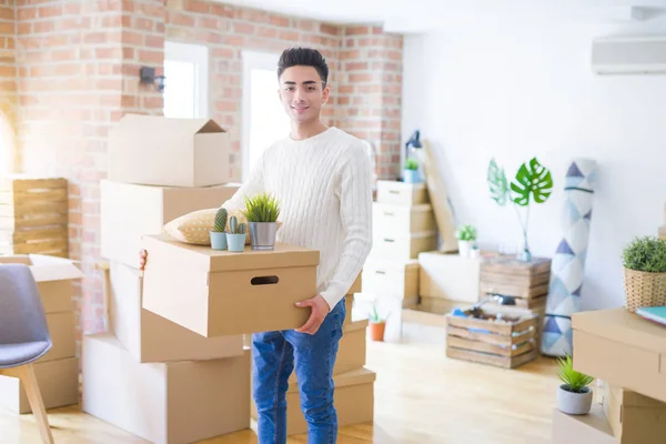 Jonge man glimlachend holdig kartonnen doos, gelukkig verhuizen naar een nieuwe Ho — Stockfoto