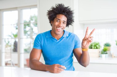 Afrika kökenli Amerikalı adam evde mutlu yüz zafer işareti yaparken kameraya göz kırpıyor ile gülümseyen. İki numaralı.