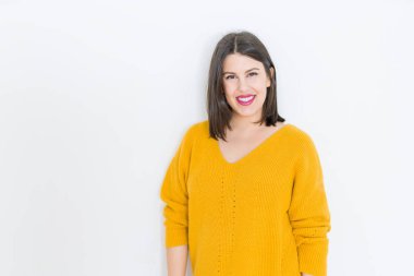Güzel esmer genç kadın kendine güvenen ve neşeli rahat sarı kazak giyen izole beyaz arka plan üzerinde gülümseyen