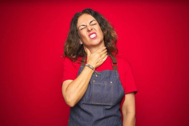 Kırmızı izole arka plan üzerinde önlük üniforma giyen orta yaş yaşlı kadın ağrılı boyun dokunmadan, grip, clod ve enfeksiyon için boğaz ağrısı