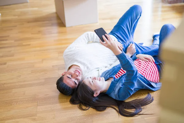 Young asian couple lyingon the floor of new house smiling happy taking a selfie photo at new apartment