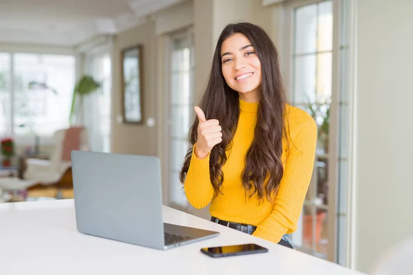 年轻女人用电脑笔记本电脑做着快乐的大拇指举手表决 用成功的表情看着摄像机 — 图库照片