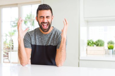 Yakışıklı İspanyol adam evde rahat t-shirt giyen silah kaldırdı ve kapalı gözleri heyecan çığlık ile başarı için deli ve deli kutluyor. Kazanan kavramı