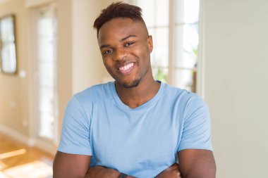 Kamera bakarak çapraz silah ile gülümseyen rahat t-shirt mutlu yüz giyen yakışıklı Afrikalı Amerikalı adam. Pozitif kişi.