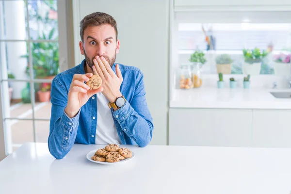 Όμορφος Άνθρωπος Που Τρώει Τσιπς Σοκολάτας Καλύπτει Στόμα Χέρι Σοκαρισμένος — Φωτογραφία Αρχείου