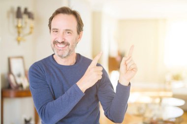 Yakışıklı orta yaş erkek ev gülümseyen ve iki elleri ve parmakları ile tarafına işaret kamera bakıyor.