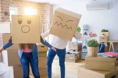 Çılgın çift kafa üzerinde komik yüzler ile kutuları giyiyor, yeni bir eve taşımak için mutlu eğlenceli