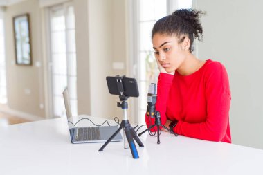 Young african american woman doing video call using smartphone camera and microphone thinking looking tired and bored with depression problems with crossed arms. clipart