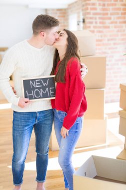 Güzel genç çift aşık ve yeni bir ev için mutlu gülümseyen yeni bir eve hareketli tahta tutarak sarılmak