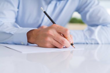 Bir kalem kağıt üzerinde beyaz masa üzerinde kullanarak yazma adam el yakın çekim