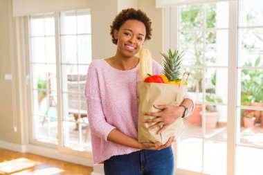 Kağıt torba dolu tutan genç güzel Afrikalı-Amerikalı kadın