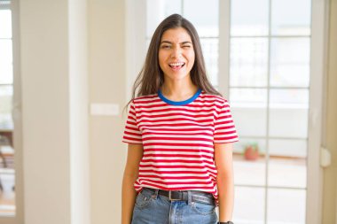 Rahat t-shirt göz kırpıyor seksi bir ifadeyle, neşeli ve mutlu yüzünü kameraya bakarak giyen genç güzel kadın.