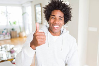 Afrikalı Amerikalı adam el ile jest kadar mutlu thumbs yapıyor Sweatshirt giyiyor. Başarı gösteren kameraya bakarak ifadeyi onaylama.