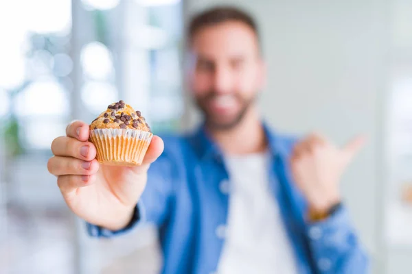 Hombre Guapo Comiendo Chips Chocolate Muffin Señalando Mostrando Con Pulgar — Foto de Stock