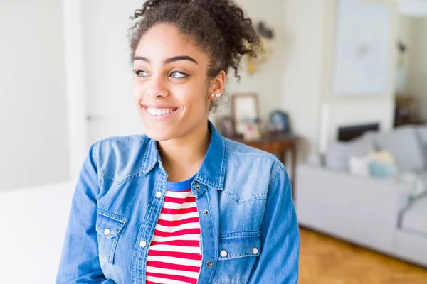 Afro saçlı rahat denim ceket görünümlü yan ve dik dik bakma uzağa düşünce gülümseyen güzel genç Afro-Amerikan kadın.