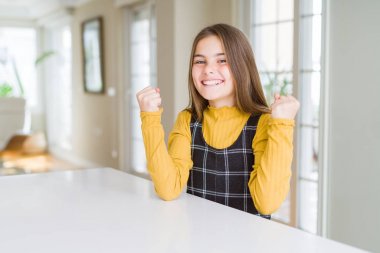 Güzel genç kız çocuk masada oturan sürpriz kutluyor ve silah ile başarı için hayran ve açık gözleri kaldırdı. Kazanan kavramı.