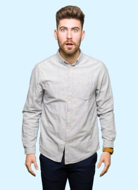 Yakışıklı delikanlı korkuyor ve şok sürpriz ifade, korku ve heyecan yüz ile rahat gömlek giymiş.