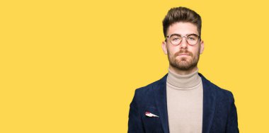 Yüzünde ciddi bir ifade ile gözlük takan genç yakışıklı iş adamı. Basit ve doğal kameraya bakıyor.