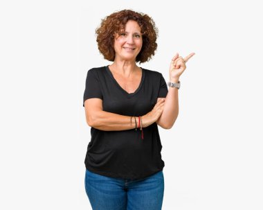 Kameraya bakarak yan el ve parmak ile işaret eden güzel orta ager üst düzey kadın yüzünde kocaman bir gülümseme ile izole arka plan.