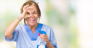 Mutlu yüz el parmaklarının arasından seyir göz üzerinde ok işaretiyle yapıyor gülümseyen izole arka plan üzerinde ev üniforma giyen orta yaş esmer temiz kadın