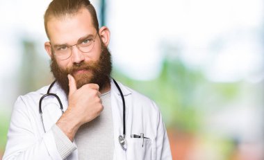 Genç Sarışın Doktor adam sakal giyen ile tıbbi kat emin çapraz kollar ve çeneme kaldırdı el ile gülümseme ile kameraya bakıyor. Pozitif düşünce.