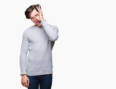 Gülümseyerek el parmakları ile mutlu yüz üzerinden seyir göz ile ok jest yapıyor izole arka plan üzerinde kış kazak giyen genç yakışıklı adam.