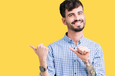 Genç yakışıklı iş adamı izole arka plan üzerinde emin gülümseyen arkasından el ve kadar başparmak ile işaret