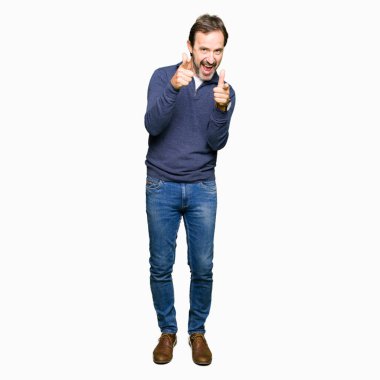 Orta yaş yakışıklı adam mutlu ve komik yüz ile kamera parmaklar işaret bir kazak giyiyor. İyi enerji ve Vibes.