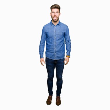 Genç yakışıklı sarışın adam dilini rahat kot gömlek giymiş out komik ifade ile mutlu. Duygu kavramı.