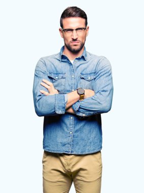 Yakışıklı adam gözlük şüpheci ve sinir, onaylamayan ifade yüz çapraz kollu giyiyor. Negatif kişi.