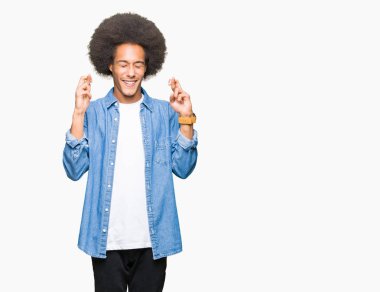 Afrikalı-Amerikalı genç afro saçlı umut ve gözleri kapalı geçiş parmaklarıyla gülümseyerek. Şans ve batıl kavramı.