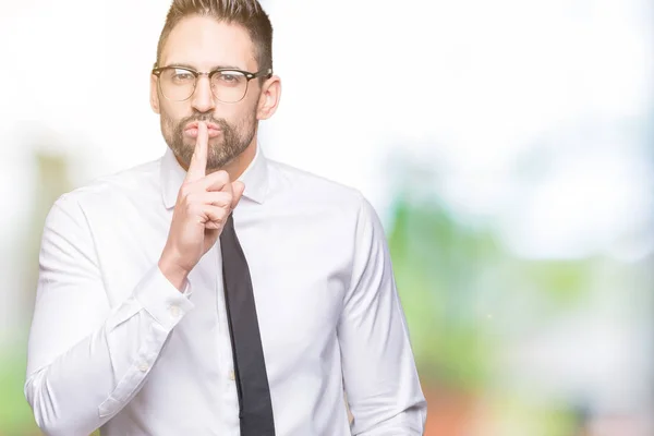 Young handsome business man wearing glasses over isolated background asking to be quiet with finger on lips. Silence and secret concept.