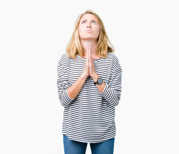 Beautiful young woman wearing stripes sweater over isolated background begging and praying with hands together with hope expression on face very emotional and worried. Asking for forgiveness. Religion concept.