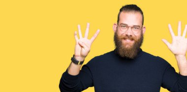 Gözlük ve gösterilen ve parmakları ile işaret boğazlı kazak giyen genç sarışın adam numara 9 kendinden emin ve mutlu gülümseyerek süre.