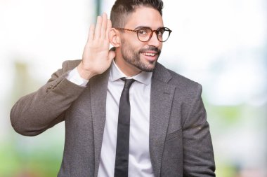 Genç yakışıklı iş adamı bir işitme söylenti ya da dedikodu için dinleme kulak üzerinde el ile gülümseyen izole arka plan üzerinde. Sağırlık kavramı.