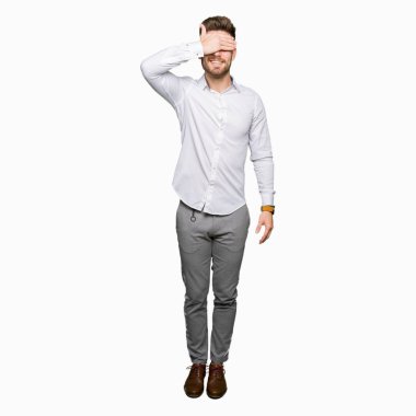 Gülümsüyor ve gözleri için sürpriz kapsayan yüz el ile gülüyor genç yakışıklı iş adamı. Kör kavramı.